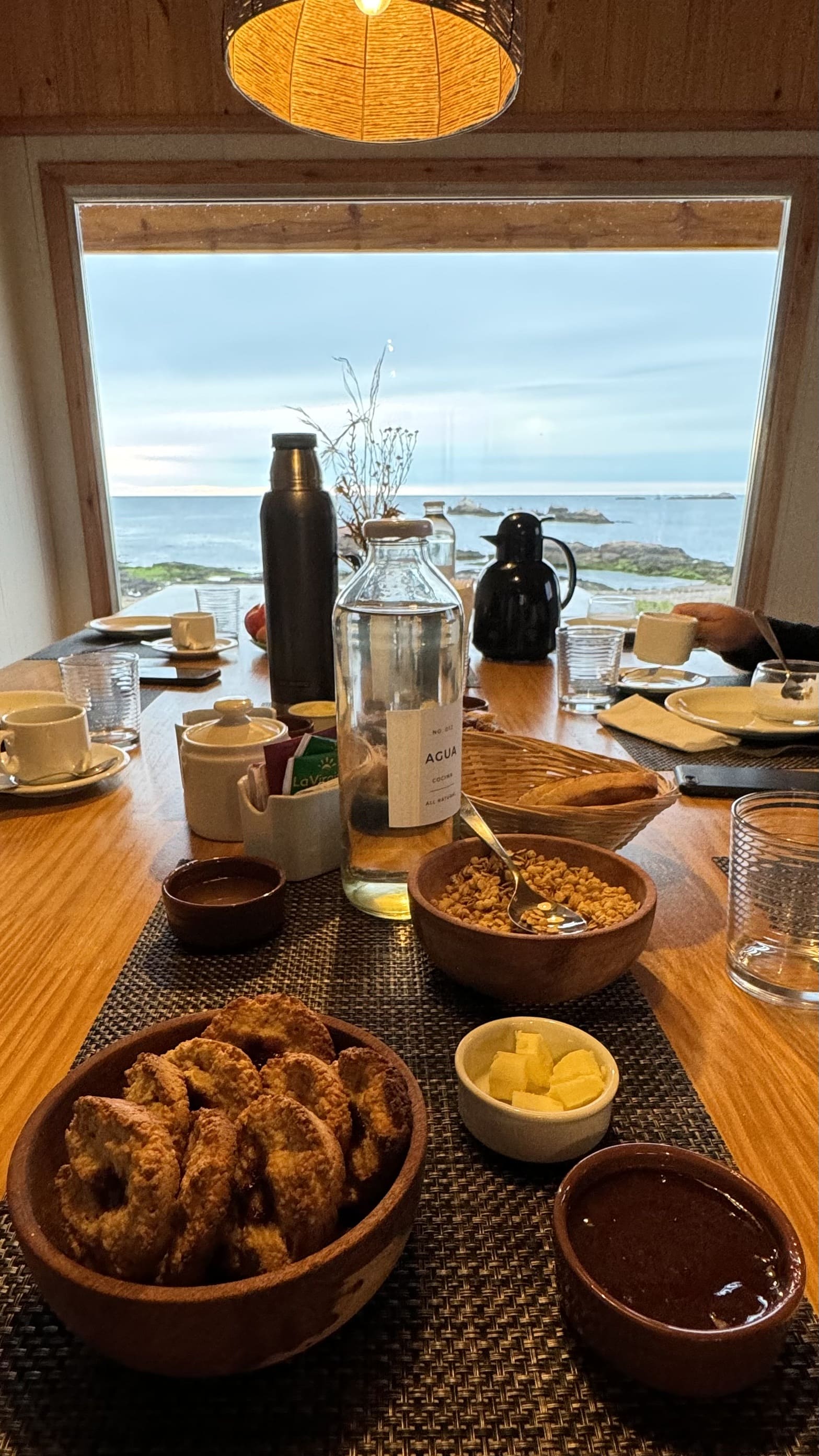 Mesa de desayuno frente a un ventanal con vista al mar en un campamento de la costa de Chubut